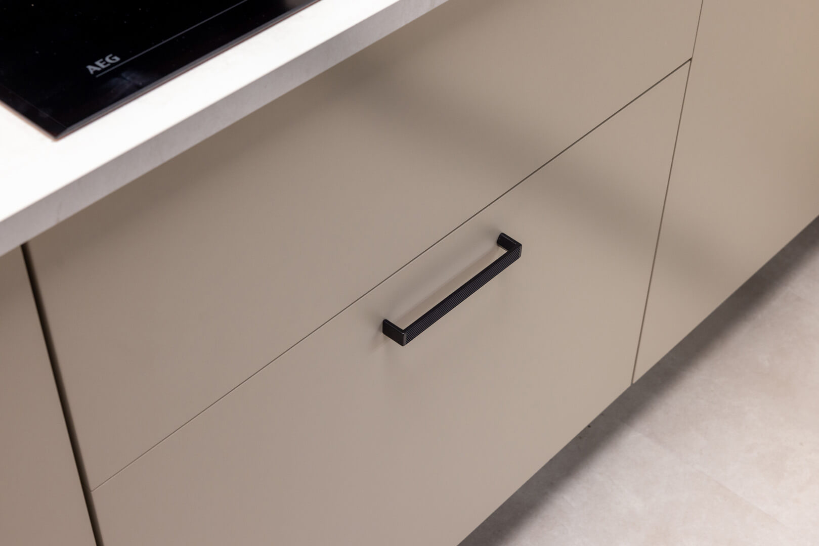 Strakke beige keuken met zwarte keukengrepen